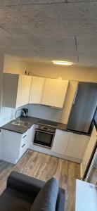 a kitchen with white cabinets and a couch in a room at RE-Seapark in Hvidovre