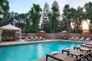 a swimming pool with tables and chairs and umbrellas at Visalia Marriott at the Convention Center in Visalia