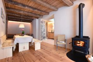 a fireplace in a living room with a table and a stove at B&B Mas de Lagorae in Tesero