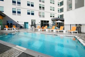 une piscine avec des chaises et un bâtiment dans l'établissement Aloft Dallas Euless, à Euless