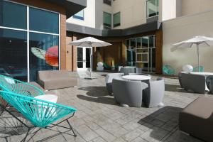 eine Terrasse mit Stühlen, Tischen und Sonnenschirmen in der Unterkunft Aloft Dallas Euless in Euless