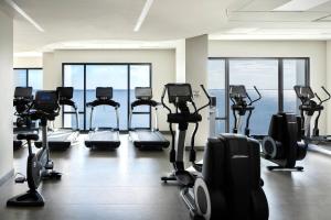 a gym with rows of treadmills and exercise bikes at The CURRENT Hotel, Autograph Collection in Tampa