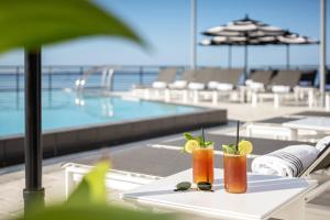 two cocktails on a table next to a swimming pool at The CURRENT Hotel, Autograph Collection in Tampa