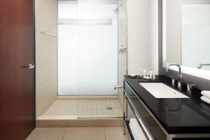 a bathroom with a shower and a sink and a mirror at Marriott Montreal Airport In-Terminal Hotel in Dorval