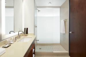 a bathroom with a shower with a glass door at Marriott Montreal Airport In-Terminal Hotel in Dorval