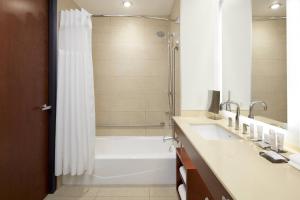 a bathroom with a tub and a shower and a sink at Marriott Montreal Airport In-Terminal Hotel in Dorval