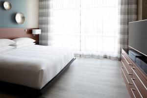 a bedroom with a white bed and a television at Marriott Montreal Airport In-Terminal Hotel in Dorval