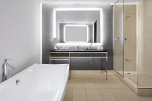 a bathroom with a sink and a mirror and a tub at Marriott Montreal Airport In-Terminal Hotel in Dorval