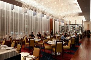 uma sala de jantar com pessoas sentadas em mesas num restaurante em Marriott Montreal Airport In-Terminal Hotel em Dorval