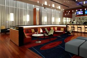 a lobby with a couch and tables and a bar at Marriott Montreal Airport In-Terminal Hotel in Dorval