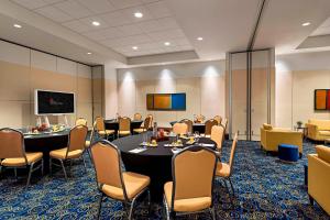 a conference room with tables and chairs and a screen at Marriott Montreal Airport In-Terminal Hotel in Dorval