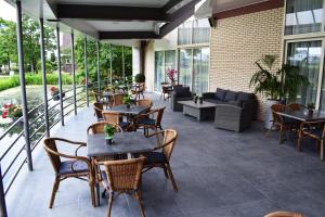 a patio with tables and chairs and a couch at Atlas Hotel Holiday in Spijkenisse