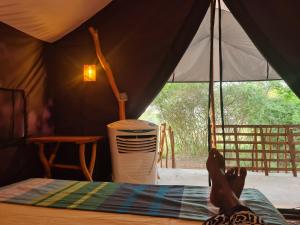 eine Person, die in einem Zelt auf einem Bett liegt in der Unterkunft Ranakeliya Lodge - Yala in Yala