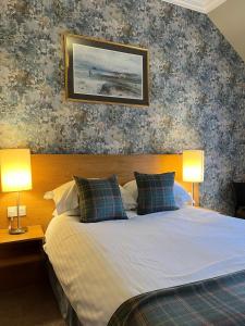 a bedroom with a bed with two lamps on it at Old Aberlady Inn in Aberlady