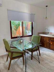 a glass table and two green chairs in a kitchen at Luana Suites- Suite Maya in Zihuatanejo