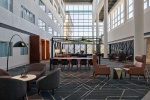 a lobby with tables and chairs in a building at Delta Hotels by Marriott Little Rock West in Little Rock