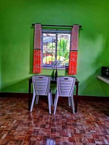 een groene kamer met een tafel en twee stoelen en een raam bij Teacher House in Phra Ae beach