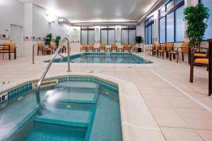 a swimming pool in a room with chairs and tables at Courtyard Rochester Mayo Clinic Area/Saint Marys in Rochester