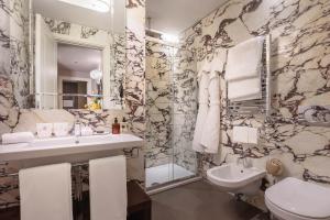 bagno con lavandino, servizi igienici e specchio di Singer Palace Hotel a Roma