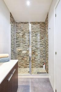 y baño con ducha y pared de piedra. en APARTAMENTO CON ENCANTO EN SOL - MADRID #B, en Madrid
