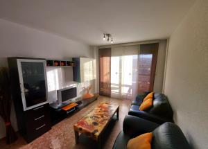 a living room with a couch and a tv at Apartamentos Milenio in Cullera