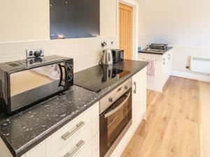 a kitchen with a microwave and a stove top oven at Granary Loft in Grantham