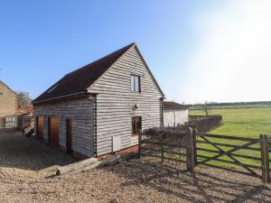 a small barn with a fence next to a field at Granary Loft in Grantham