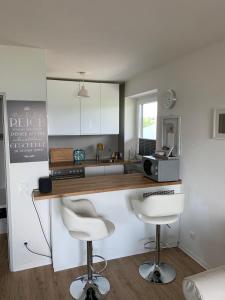 a kitchen with a counter and two bar stools at Apartment am See in Scharbeutz