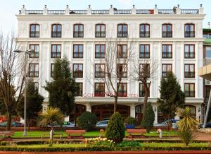 ein weißes Gebäude mit Bänken davor in der Unterkunft Deluxe Golden Horn Sultanahmet Hotel in Istanbul