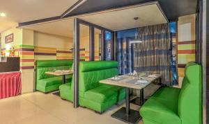 un restaurante con mesas y sillas verdes en una habitación en Treebo Tryst Metropolis en Hyderabad