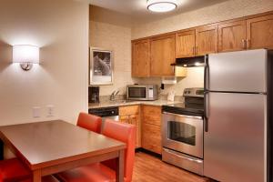 cocina con mesa y nevera de acero inoxidable en Residence Inn Salt Lake City Sandy, en Sandy