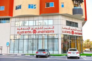 two cars parked in front of a building at Alain Hotel Apartments Ajman in Ajman 