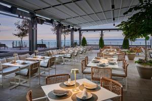 a restaurant with tables and chairs with the ocean in the background at The Pearle Hotel & Spa, Autograph Collection in Burlington