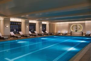a swimming pool in a hotel with chairs and a table at The Ritz-Carlton, Tokyo in Tokyo