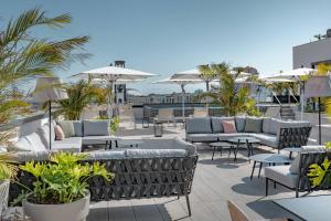 聖克魯斯－德特內里費的住宿－AC Hotel by Marriott Tenerife，屋顶庭院配有沙发、桌子和遮阳伞
