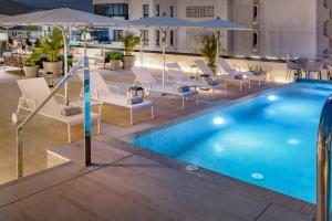 聖克魯斯－德特內里費的住宿－AC Hotel by Marriott Tenerife，一座带椅子和遮阳伞的游泳池位于一座建筑旁边