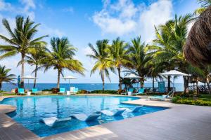 uma piscina com palmeiras e o oceano em Margaritaville Island Reserve Riviera Cancún - An All-Inclusive Experience for All em Puerto Morelos