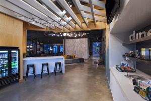 a bar in a restaurant with stools and a counter at Aloft Little Rock West in Little Rock