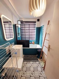 uma casa de banho azul com um lavatório e uma banheira em Appartement à 100m de la plage 7 nuits minimum haute saison em Sainte-Maxime