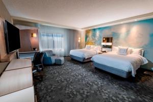 a hotel room with two beds and a flat screen tv at Courtyard by Marriott Tampa Northwest/Veterans Expressway in Tampa