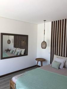 1 dormitorio con cama y espejo en la pared en Jardim do Olival - Casa com piscina en Correlhã