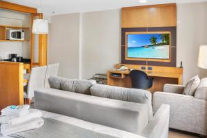 a living room with a couch and a desk and a television at Hotel Corporativo na Faria Lima in Sao Paulo