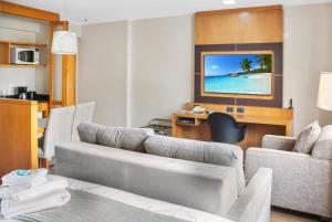 a living room with a couch and a desk and a television at Hotel Corporativo na Faria Lima in São Paulo