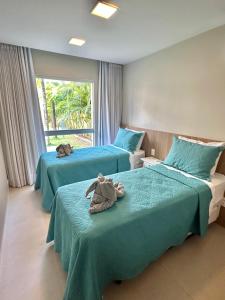 a bedroom with two beds with stuffed animals on them at Porto Smeralda Guarajuba C001 in Guarajuba
