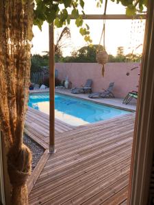 a swimming pool with a wooden deck and a pool at Villa des Oliviers in Baillargues