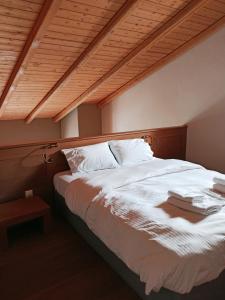 a bedroom with a large white bed with a wooden ceiling at Guesthouse Vasiliki in Steni Dirfyos