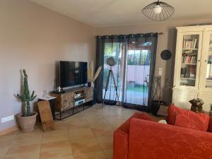 a living room with a couch and a tv at Villa des Oliviers in Baillargues