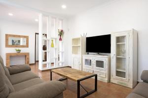 a living room with a tv and a couch and a table at Vivienda Rural El chiclanero in Conil de la Frontera