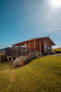 a wooden cabin with a porch on a grass field at Refúgio do Sol Campestre in Urubici