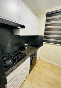 a kitchen with white cabinets and a stove top oven at Yas 2 Apartment in Samarkand +5 photos
